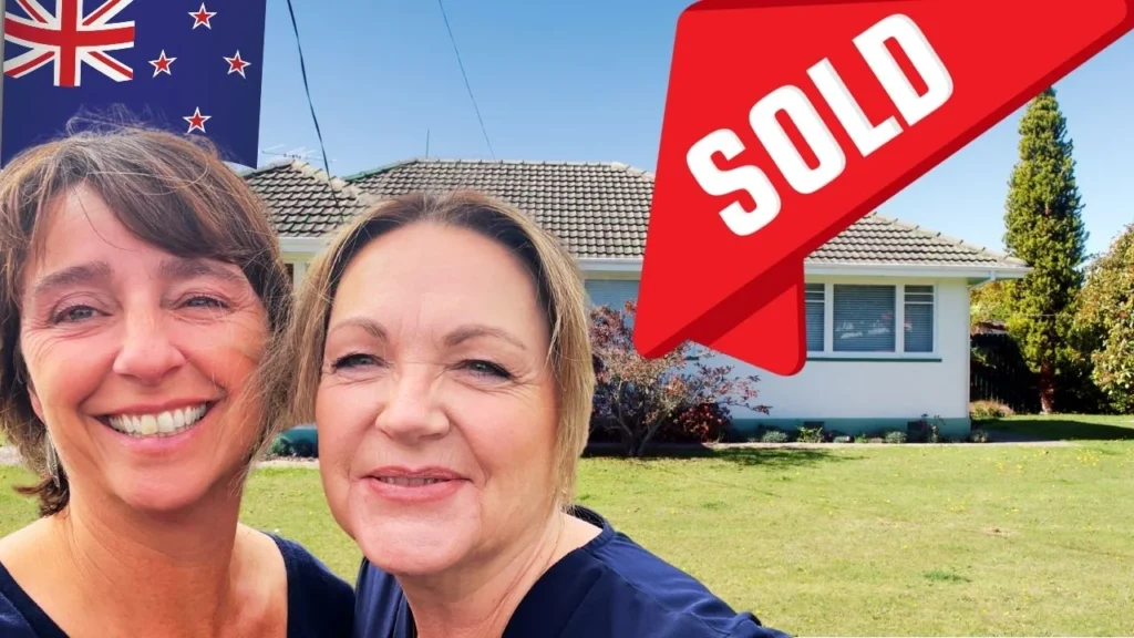 Two friends standing in front of a house in new Zealand talking about how to buy a house in New Zealand 